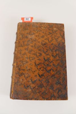 un vieux livre posé sur une table blanche, à côté d'une étiquette rouge