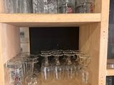 bottles and glasses on a shelf in a store with a chalk board in the background