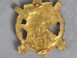 a close up of a gold brooch on a white surface