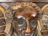a wooden sculpture of a man with two angels on his head