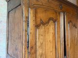 une armoire en bois dont la porte est ouverte, dans une pièce