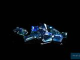 blue crystals are scattered on a black surface with a black background