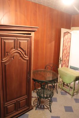 a cabinet and table in a room with wood paneling on the walls
