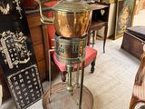 a large copper pot sitting on a stand in a room