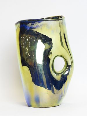 a close up of a blue and yellow vase with a hole in it