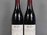 two bottles of red wine sitting on top of a glass table