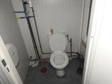 a toilet in a small room with pipes and pipes