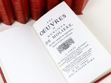 an open book sitting on top of a table next to a bunch of red books
