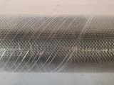 a close up of a roll of metal mesh on a white surface