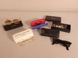 several pairs of sunglasses, sunglasses, and a case on a table