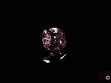 a pink diamond on a black surface with a black background