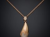 un pendentif en or et diamants suspendu à une chaîne, sur fond noir