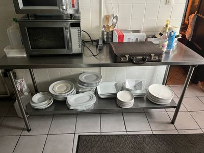 table en acier inoxydable sur laquelle sont posés des assiettes et des bols, dans une cuisine professionnelle