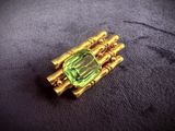 a close up of a green and gold broochle on a black surface