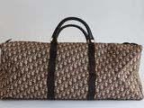 un sac de voyage marron et noir posé sur une surface blanche