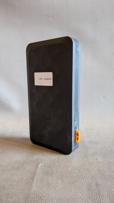 une petite boîte noire posée sur une surface blanche