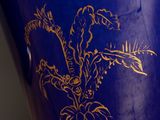 a blue vase with gold designs on it on a table
