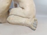 a statue of a man sitting on the ground
