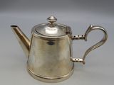 an antique silver teapot with a handle on a white surface