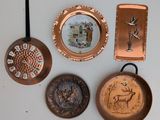 four copper pans and a plate with a deer on them