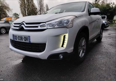 the front of a white citrole is parked in a parking lot
