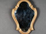 a mirror hanging on the wall with a gold frame