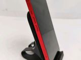 a close up of a cell phone on a stand on a white surface