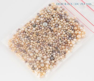 un sachet de perles posé sur une table blanche, orné d'un ruban rouge