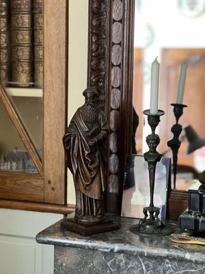 une statue représentant un homme assis sur une cheminée, à côté d'un miroir