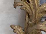 a gold mirror on the wall next to a chair