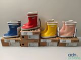 several pairs of children ' s rain boots are lined up on boxes