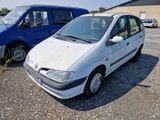 a small white car parked in a lot next to a blue van