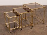 trois tables gigognes en métal doré et en verre, montées sur des pieds en forme de cornes