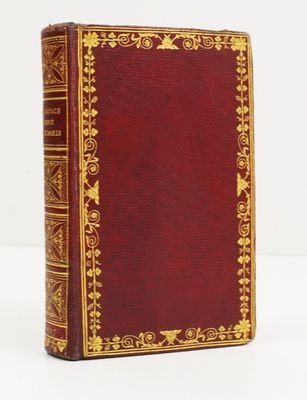 un livre rouge avec des bordures dorées posé sur une surface blanche