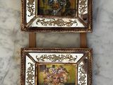 two picture frames hanging on the wall with tassels