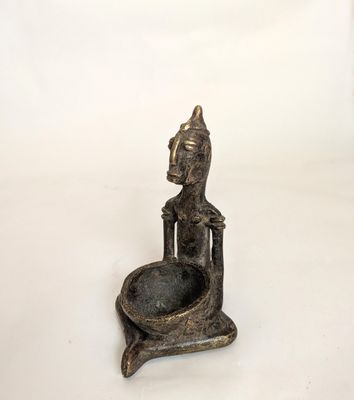 an old bronze statue of a person sitting on a bowl