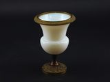 a white vase with a gold rim sitting on a black surface