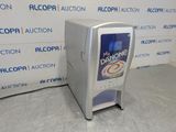 a soda machine sitting on the floor in front of a wall