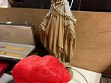 a red heart on a table next to a statue of a woman