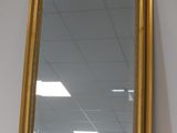 gold framed mirror on a shelf in a room with a white wall