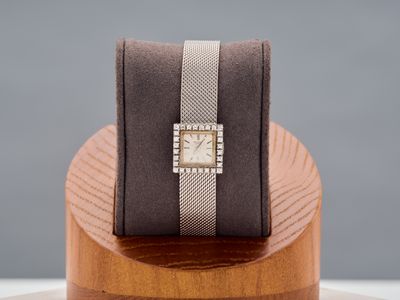 an image of a watch sitting on top of a wooden stand