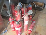 many fire extinguisors sitting on the floor next to a stove