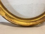 a picture of a gold oval mirror on a wall