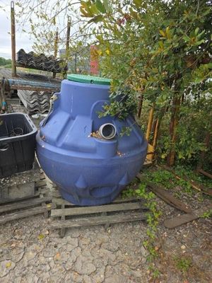 un grand réservoir d'eau bleu posé à côté d'une poubelle noire