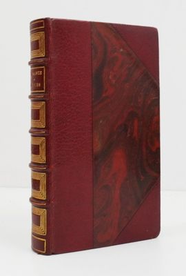 an old book with a red cover sitting on top of a white table