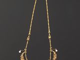 a gold necklace with pearls on a black background