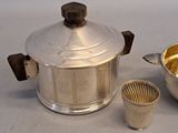 a silver pot and a silver cup on a table