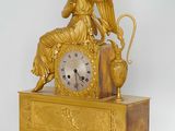 a gold clock with an angel sitting on top of it