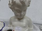 a white statue of a child with a cup and saucer