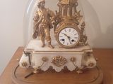 une horloge placée sous un dôme de verre sur une table